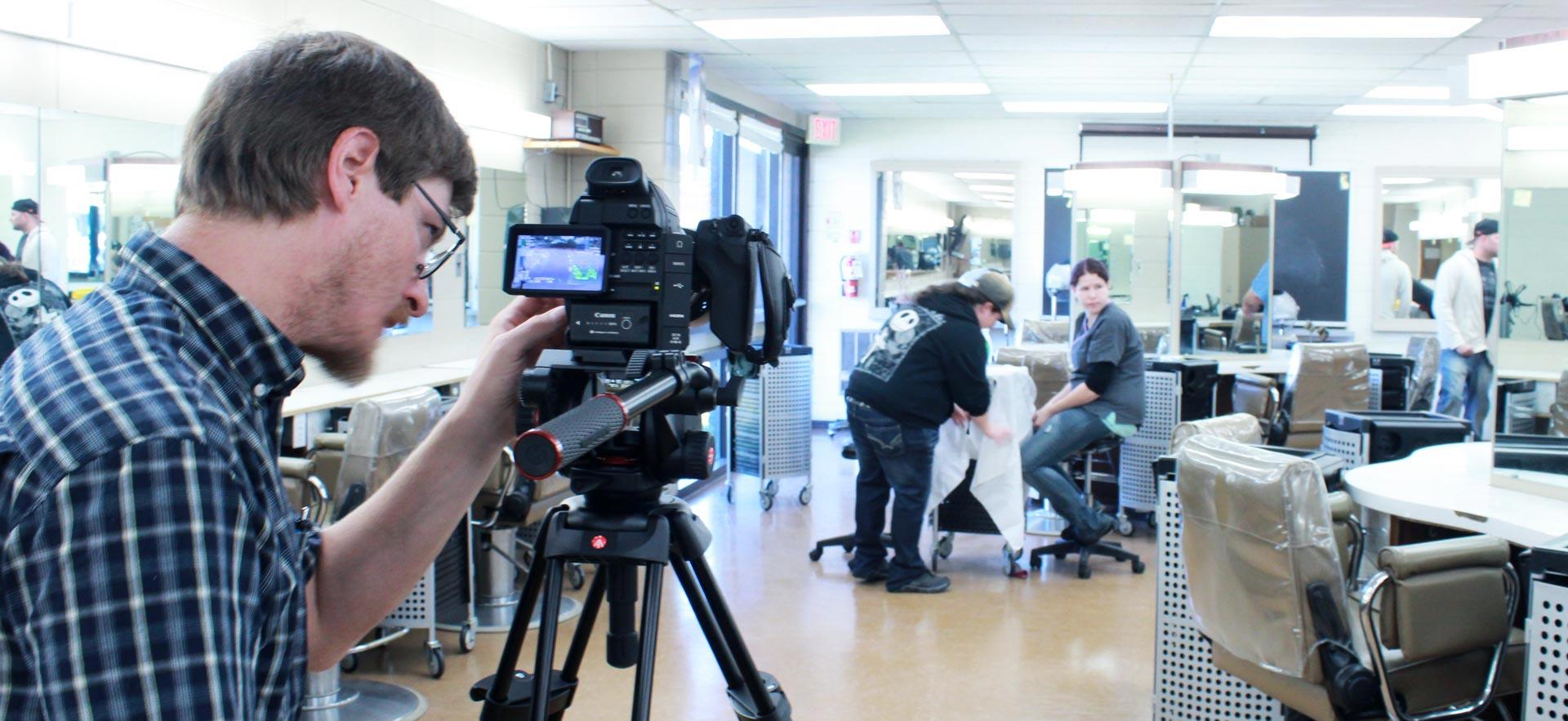 Male digital video student shoots video in the о hairstyling salon.