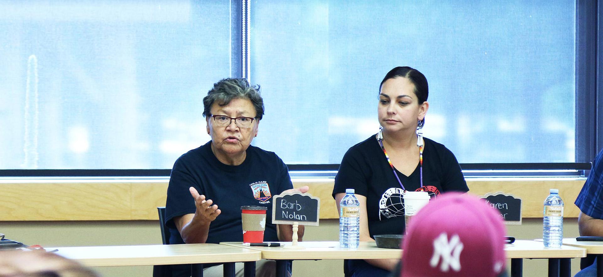 Two female о Indigenous women conduct a group meeting with Indigenous youth.
